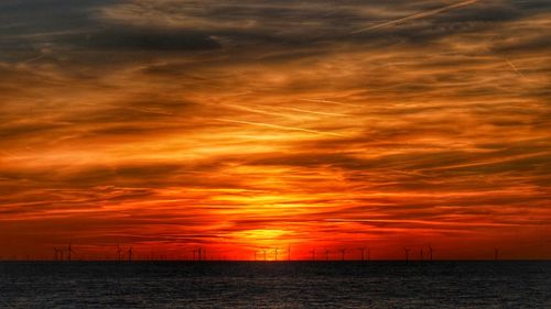 Scenic view of sea against dramatic sky during sunset