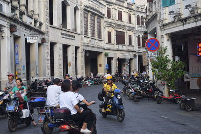 People riding motorcycle on road in city