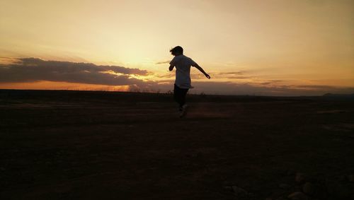 Full length of silhouette man standing on field against sky during sunset