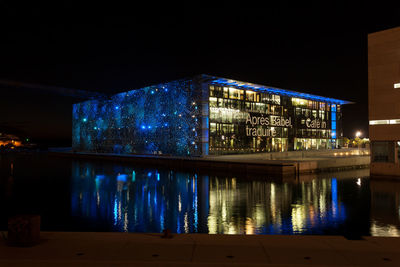 Illuminated buildings by river at night