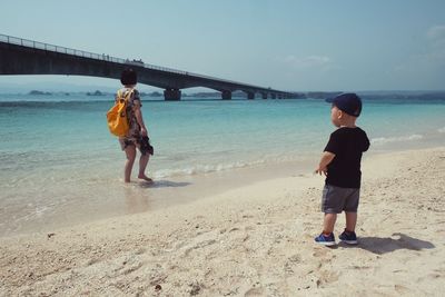 Full length of boy standing on beach against sky