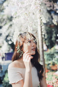 Midsection of woman with arms raised standing against plants