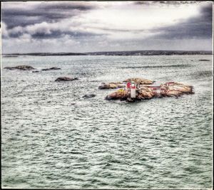 Boats in sea against cloudy sky