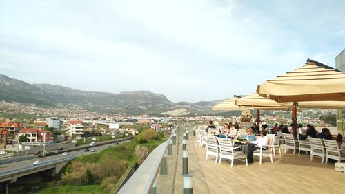 Group of people in restaurant by buildings in city against sky