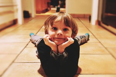 Portrait of cute boy lying on floor at home