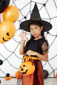 Portrait of young woman with arms raised standing on halloween