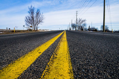 Surface level of double yellow line on road against sky