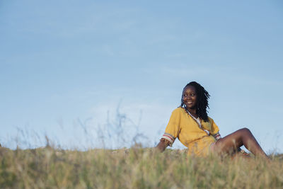 Woman looking away on field against sky