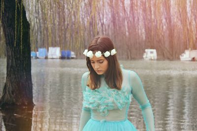 Young woman in turquoise dress looking down against lake