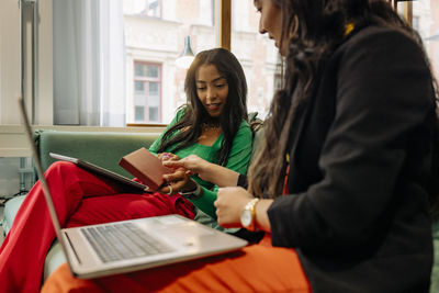 Female business colleagues discussing over box while sitting at workplace