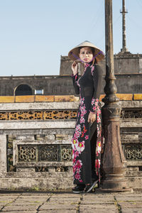 Portrait of woman standing against building