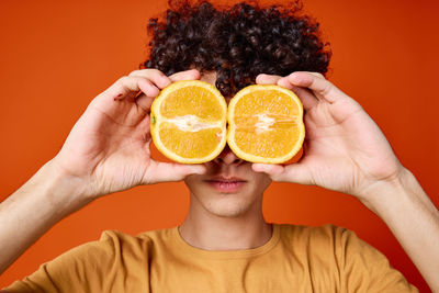 Portrait of woman with orange fruit against gray background