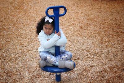 High angle view of girl sitting on outdoor play equipment