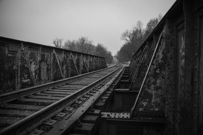 Railroad tracks by trees against clear sky