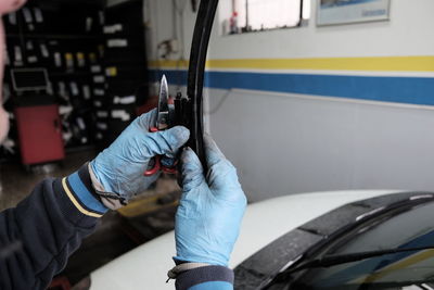 Cropped hands of mechanic holding windshield wiper against car at auto repair shop