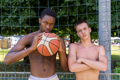 Portrait of two young multiethnic basketball players on the playing field on a sunny summer day