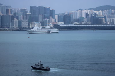 Ship sailing in sea against buildings in city