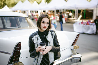 Portrait of beautiful woman having coffee by car on road