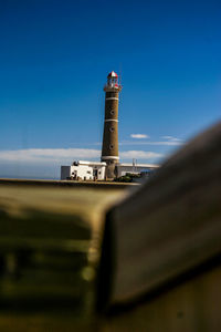 Low angle view of lighthouse by building against sky