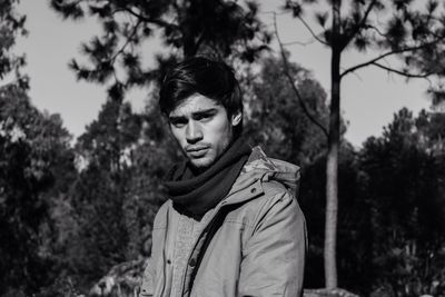 Close-up portrait of young woman standing against trees