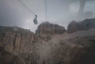 Overhead cable car in mountains against sky