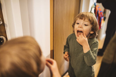 Boy standing in front of mirror with open mouth