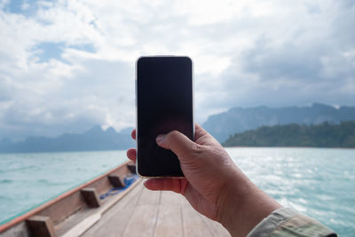 Midsection of man using mobile phone against sky