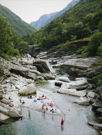 High angle view of people on cliff by mountain against sky