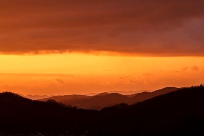 Silhouette mountains against dramatic sky during sunset