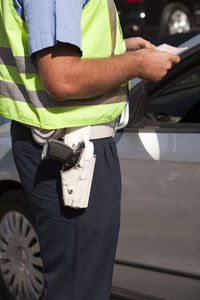 Midsection of man standing by car