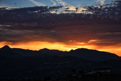 Scenic view of silhouette mountains against orange sky