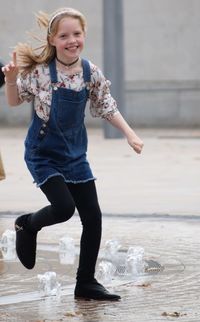 Portrait of smiling girl playing in fountain on street