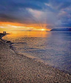 Scenic view of sea against dramatic sky during sunset