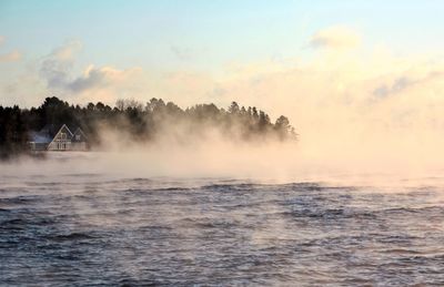 Scenic view of misty lake during sunset
