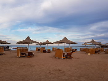 Lounge chairs on beach against sky