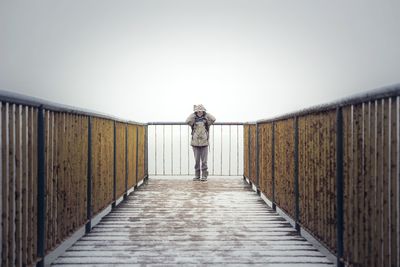 Woman standing at observation point against clear sky during winter