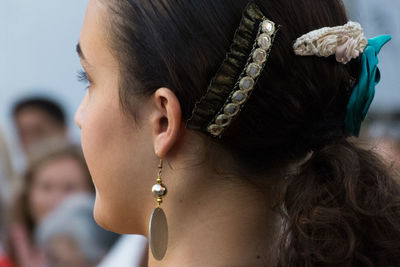 Side view of young woman wearing earring and hair accessory outdoors