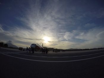 People riding bicycle on road against sky during sunset