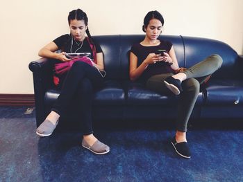 Young women using mobile phone while sitting on sofa