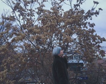 Side view of man standing by tree