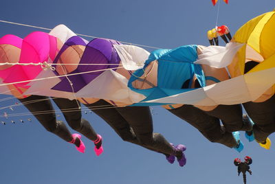 Low angle view of umbrellas hanging against blue sky