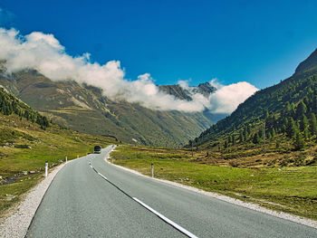 Road leading towards mountains against sky