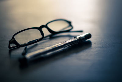 Close-up of eyeglasses with pen on table