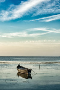 View of rowboat at shore against sea and sky