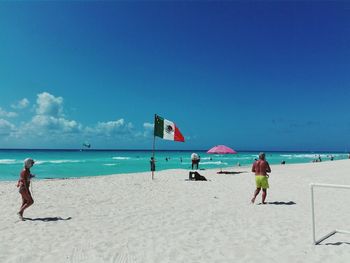 People by portugal flag at beach against sky