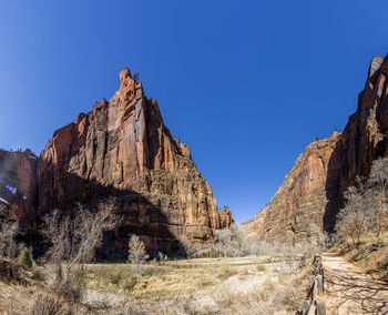 Low angle view of rock formations against clear blue sky