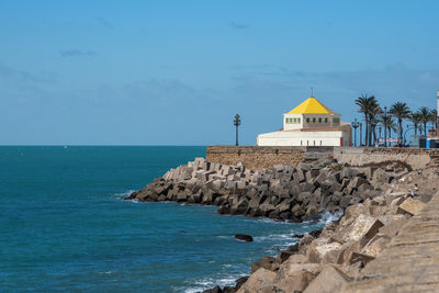 Lighthouse by sea against sky