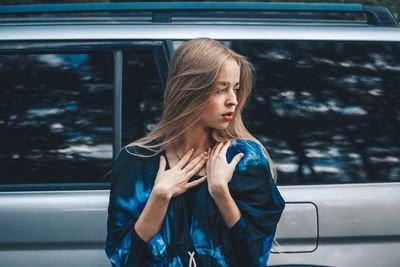 Young woman standing against car