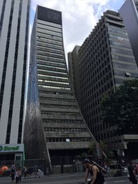 People on modern buildings in city against sky