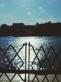 Silhouette cityscape by sea against sky